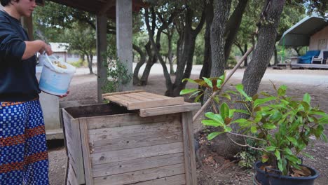 person throwing food waste into a compost practicing sustainable lifestyle in a ecological farm