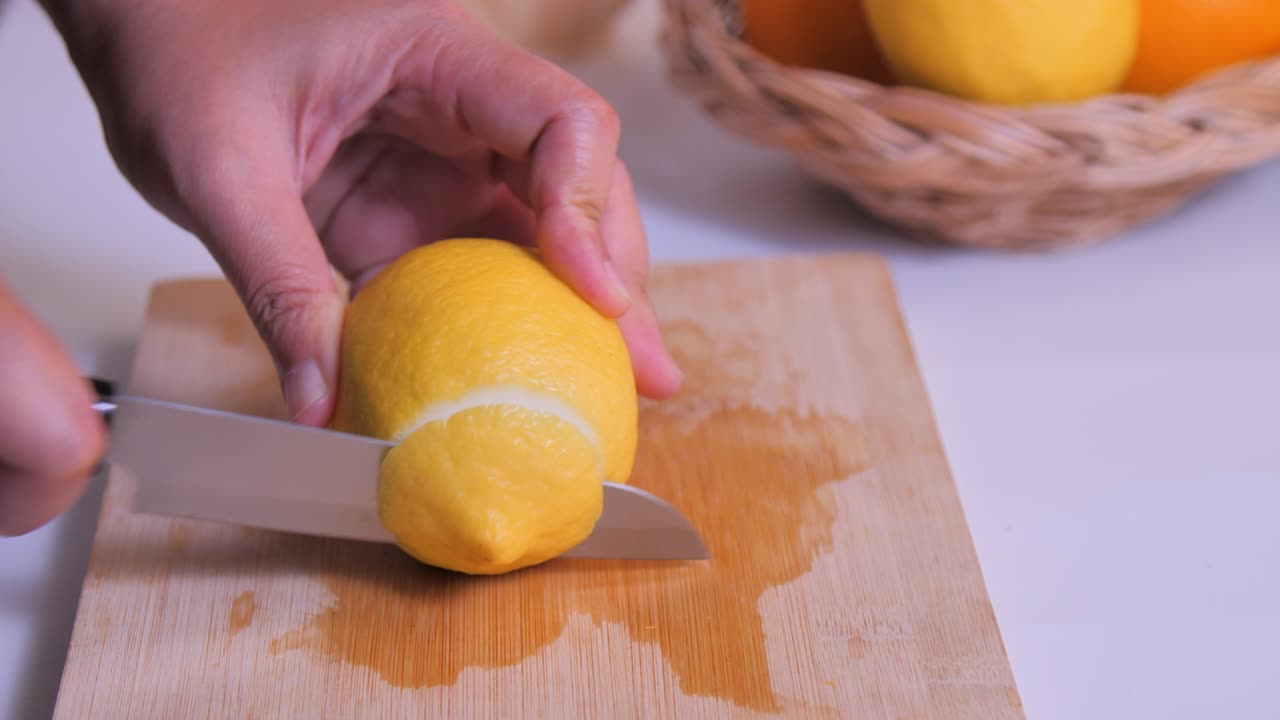 Close-up slice the lemon on the cutting board in the kitchen