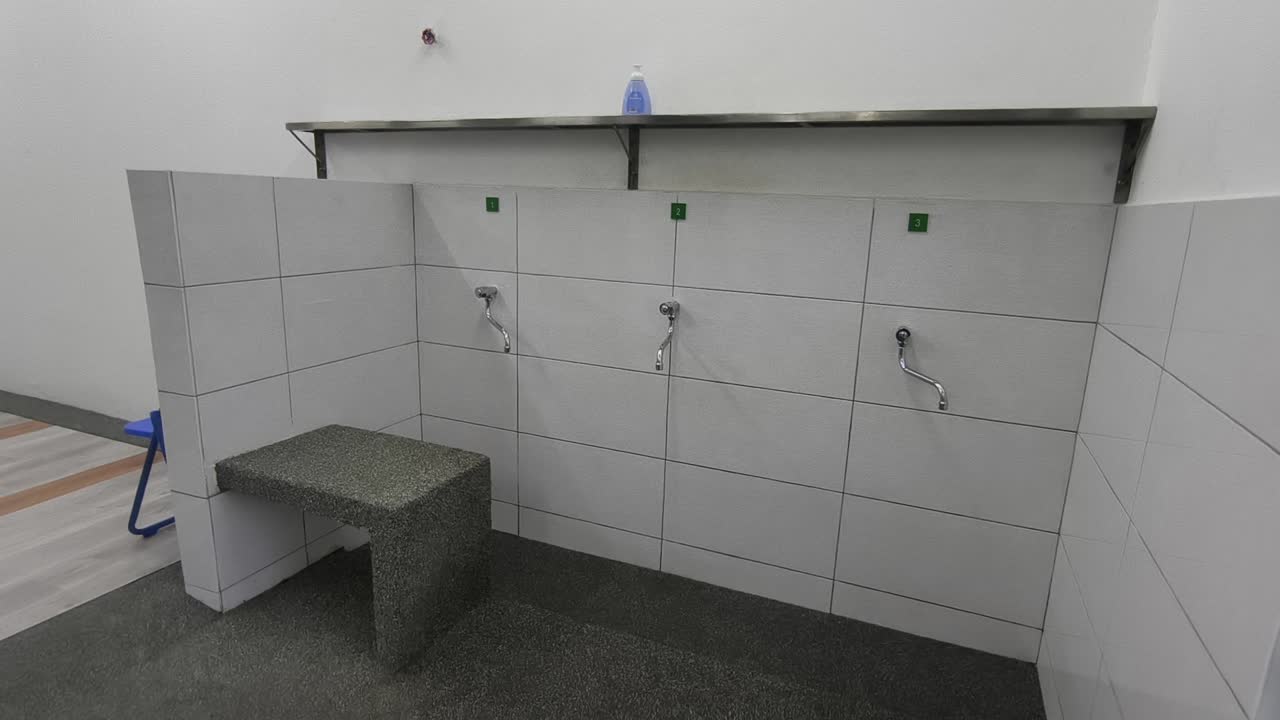 A close-up of a clean ablution area at a small Malaysian highway prayer room. Water flows for ritual washing as travelers prepare for prayer
