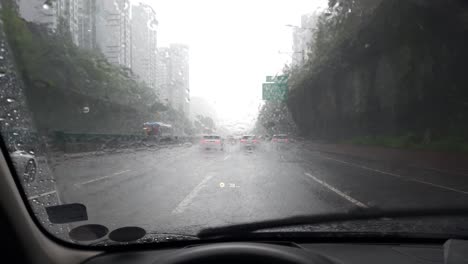 driver drives the car in heavy rain on gangnam highway in seoul city, view through the windshield of the car