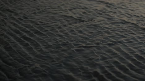 incoming tide covering dark sand