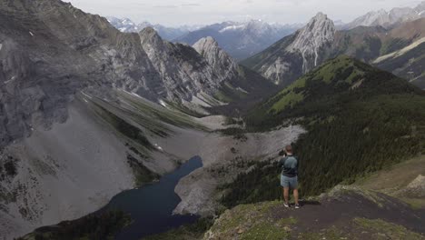 Hiker-taking-photos-of-lake-view-on-ridge-Rockies-Kananaskis-Alberta-Canada
