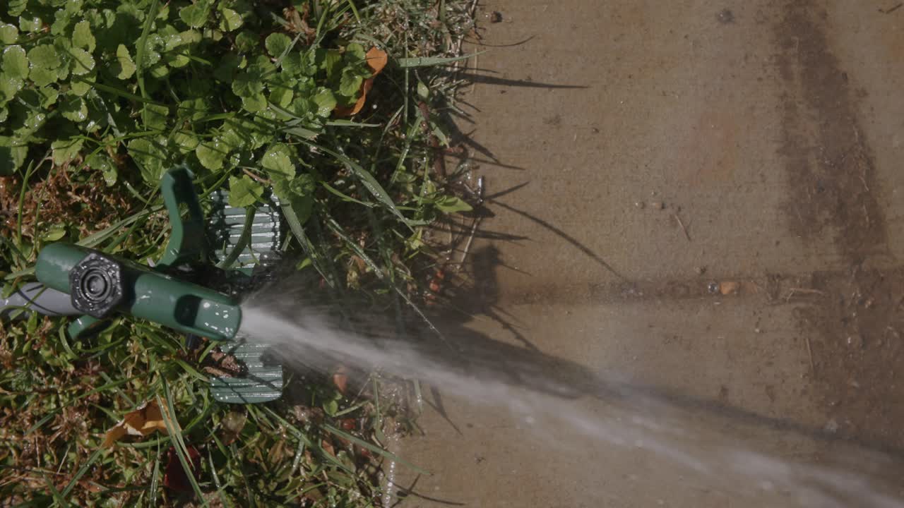 보도 옆 마당에 물을 주는 스프링클러의 하향식 클로즈 모션 영상