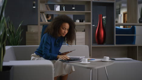 mujer profesional afroamericana llama por teléfono usando una tableta en la oficina.