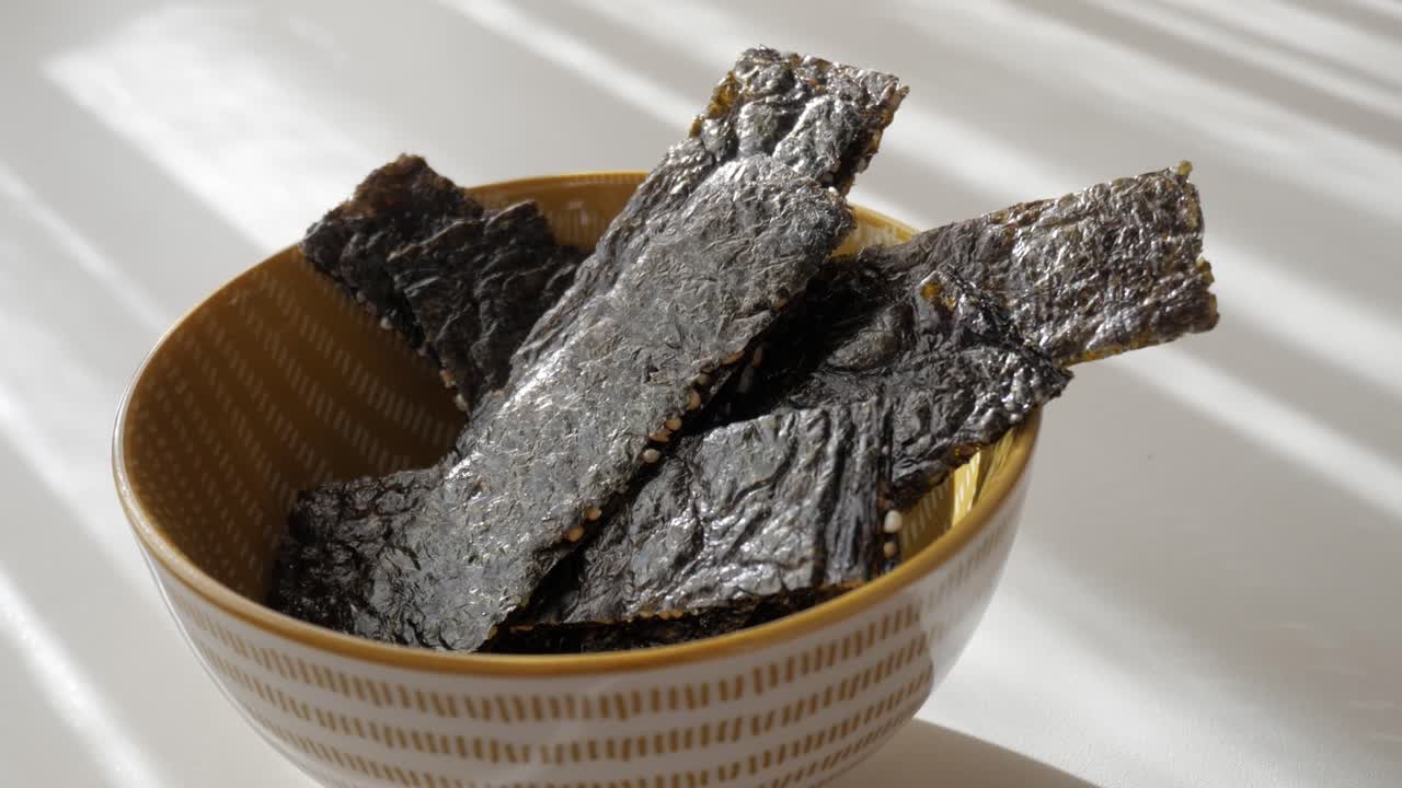 Crispy seaweed snack in a bowl, captured in natural daylight indoors
