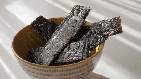 crispy seaweed snack in a bowl, captured in natural daylight indoors
