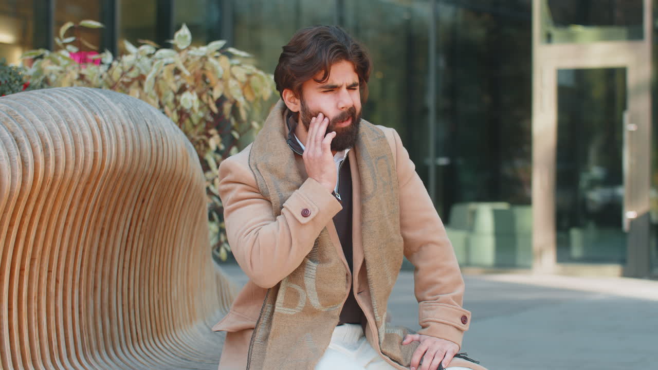 Mature indian businessman feeling toothache bad unpleasant symptoms suffering from pain outdoors