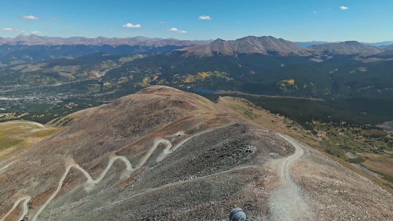 Scenic dirt road ascending Peak 10 in Breckenridge, captured from an aerial view, surrounded by rocky terrain with radio tower station at top