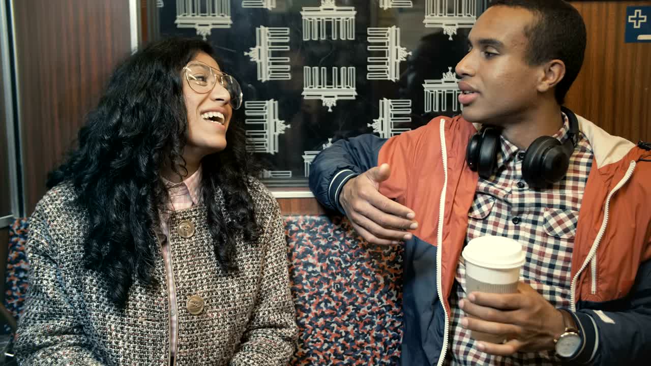 Donna mediorientale e un uomo africano che viaggiano in treno nella metropolitana di Berlino e parlano.