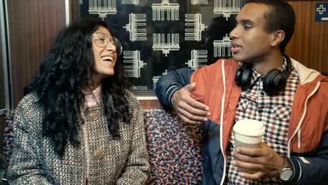 middle eastern woman and an african man traveling on a train in berlin underground and talking
