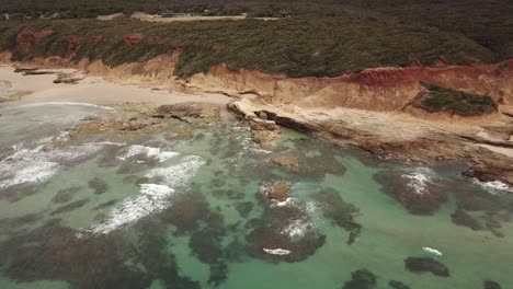 antena de drones con un largo zoom para revelar agua azul clara y hermosa y un paisaje rocoso como el marte
