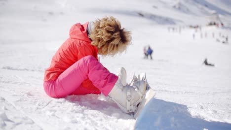 skier putting on her snowboard