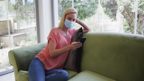 Woman-wearing-face-mask-using-smartphone-at-home