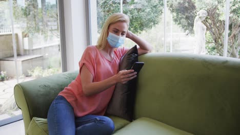 woman wearing face mask using smartphone at home