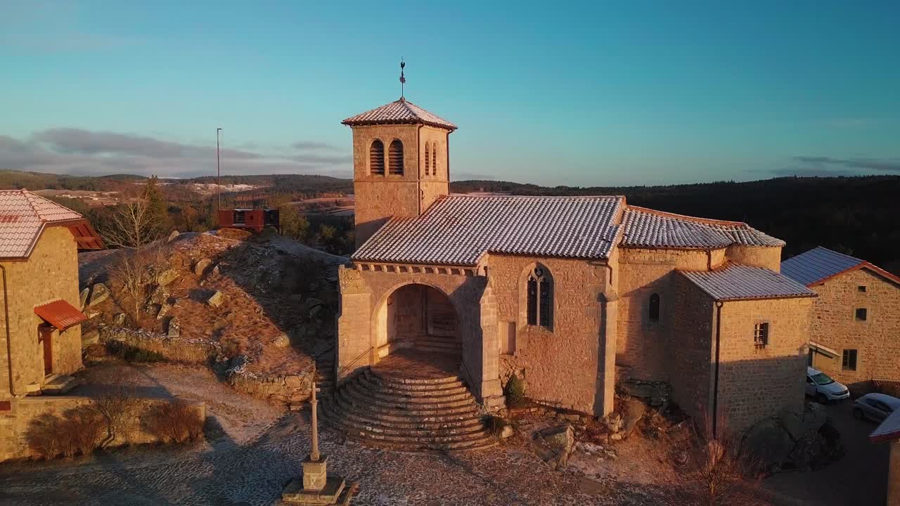 aerial wide shot around a medieval church in the small town of Montarcher in Loire departement on a frosty morning, Auvergne Rhone Alpes region, France