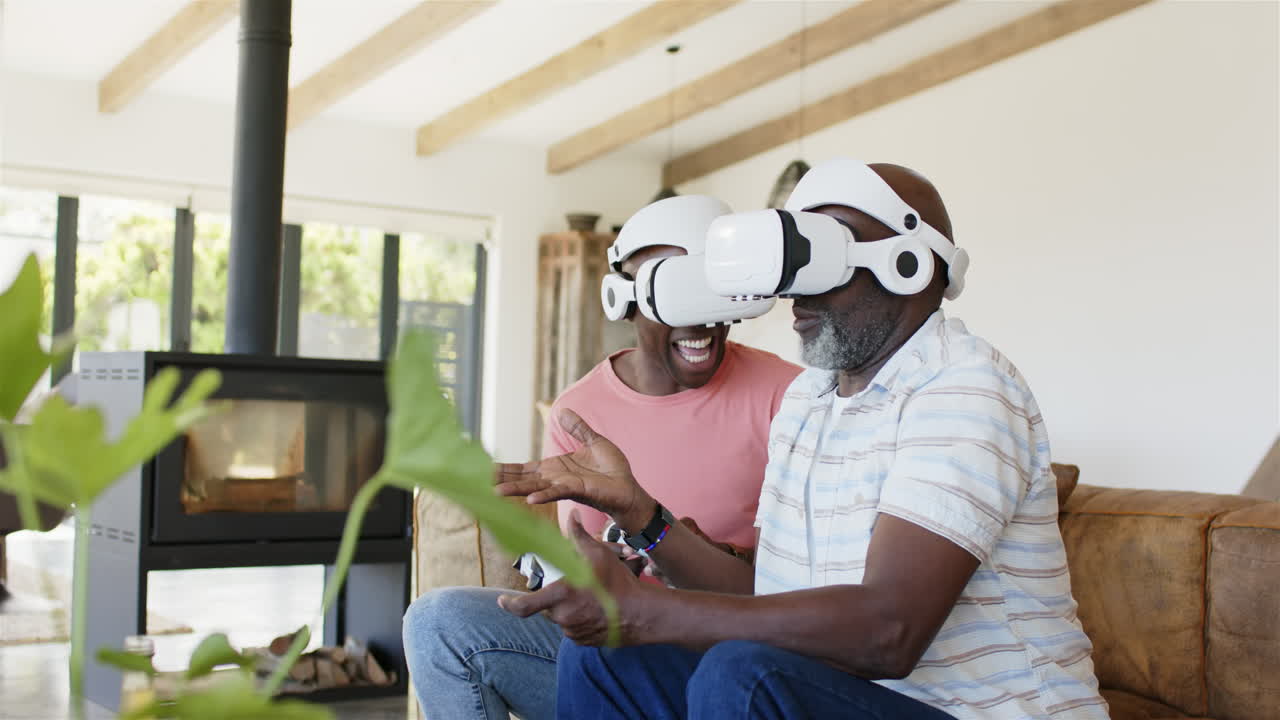 Indossando visori VR, padre e figlio ridono e si godono un gioco di realtà virtuale.