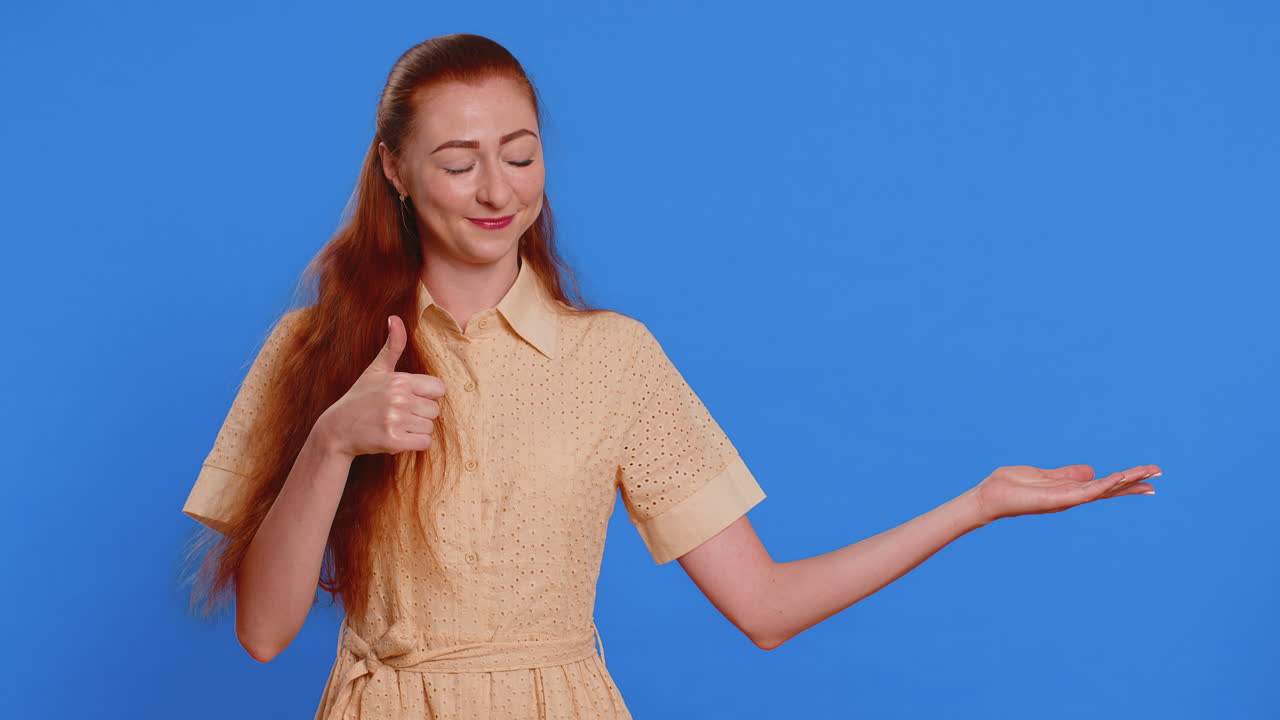 mujer joven mostrando los pulgares hacia arriba y apuntando a la derecha en el espacio en blanco lugar para su logotipo de publicidad