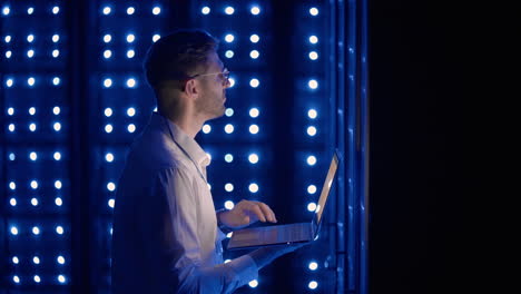 male server engineer in data center. it engineer inspecting a secure server cabinet using modern technology laptop coworking in data center.