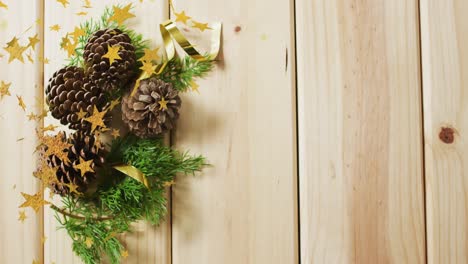 Animation-of-stars-falling-over-pine-cones-and-wooden-background-with-copy-space