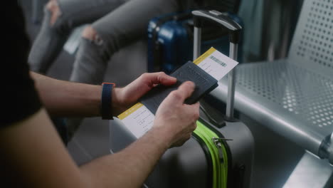 person holding passport and boarding pass near luggage at airport.