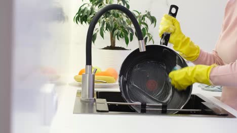 woman washing frying pan in kitchen sink