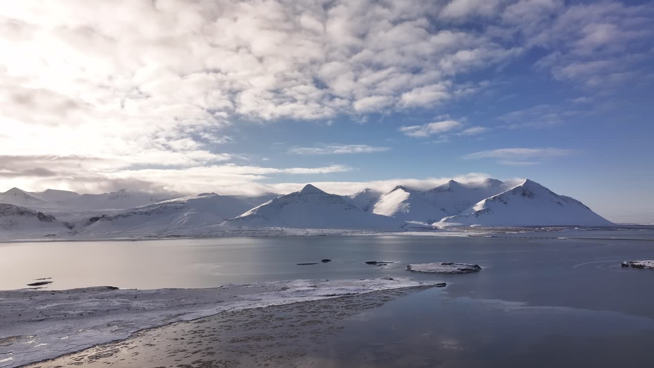 Snowy mountains reflect on calm waters at Borgarfjörður, near Borgarnes, Iceland.