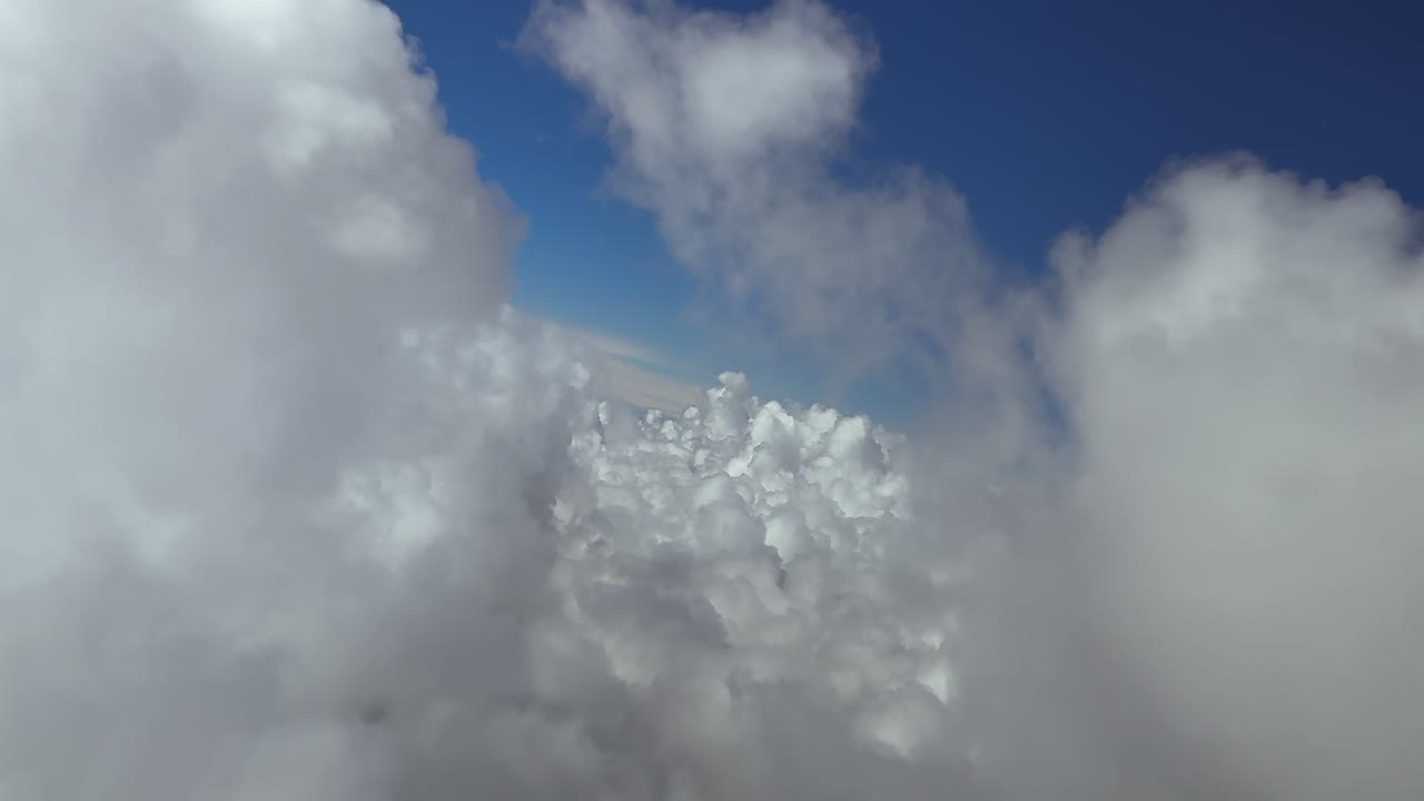 An immersive pilot’s perspective recorded from a jet cockpit flying through cottony clouds, doing some turns, under a deep blue sky