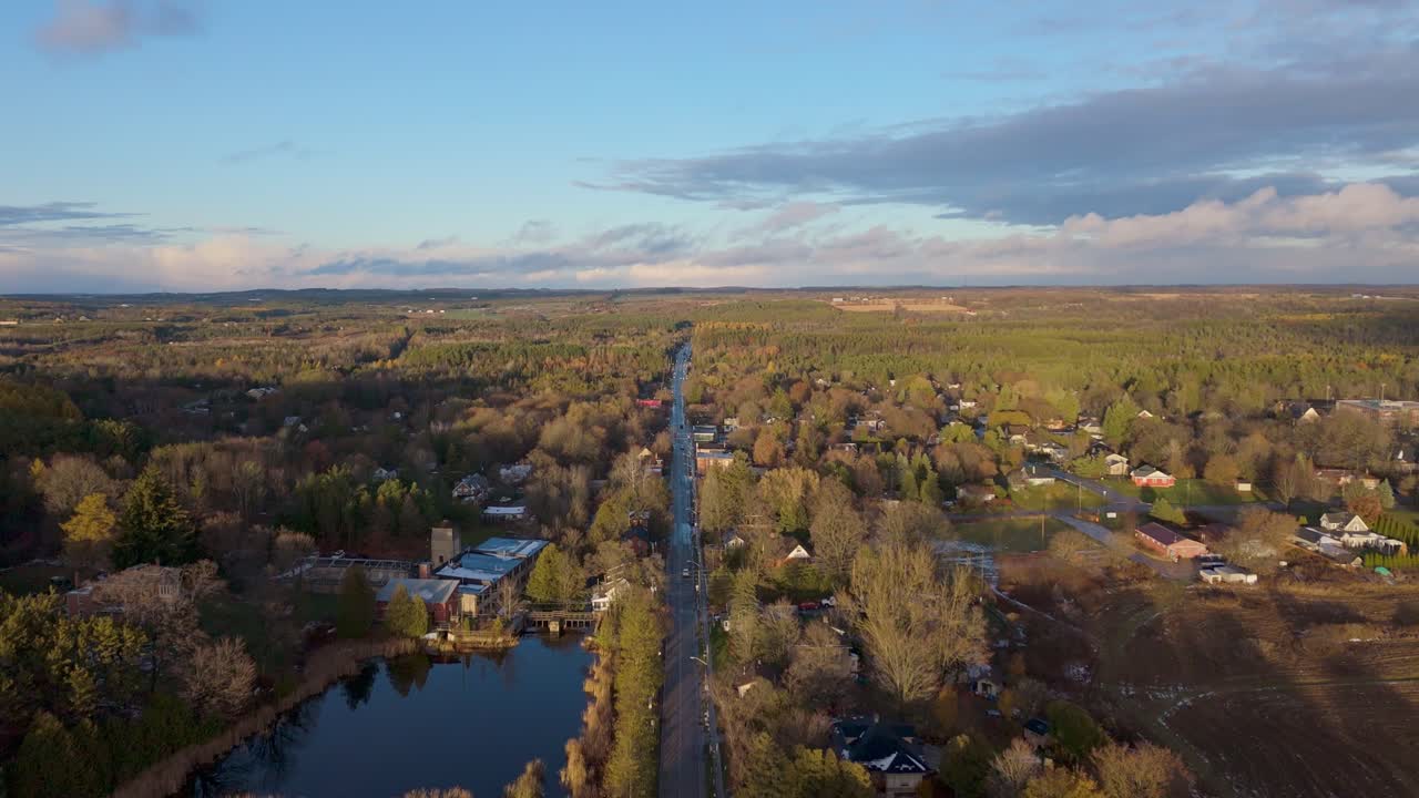 Zpětný pohled dronu nad městem Alton v Caledonu, Ontario, odhalující malou venkovskou komunitu obklopenou lesem, zvlněným terénem a večerním světlem napříč krajinou.