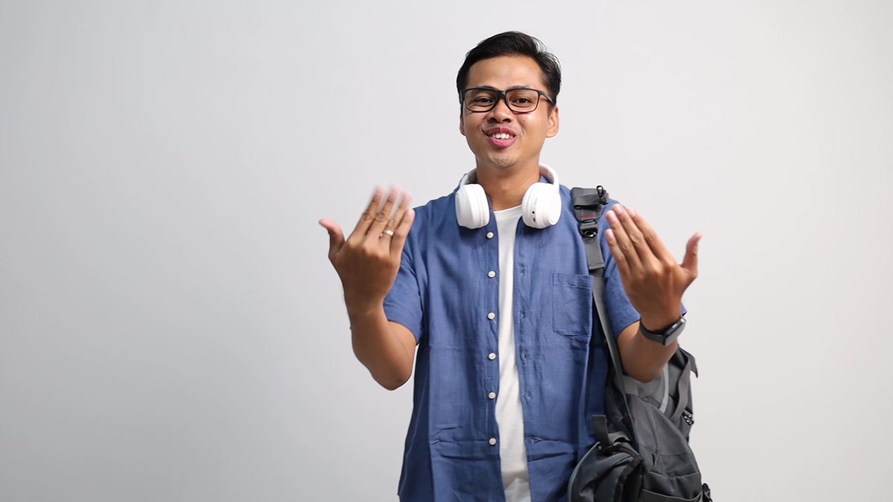 Attractive young asian college student look at camera see you, wave hand, come to me, gesturing hi, welcoming with raised hand.