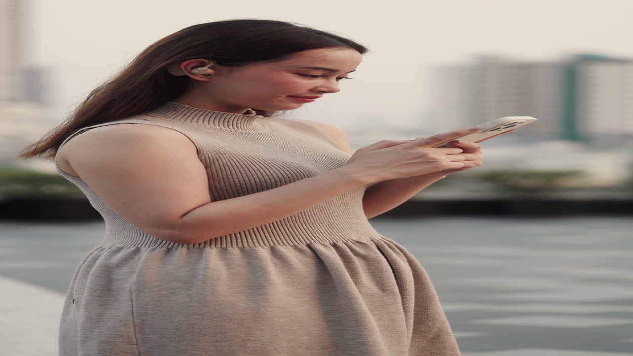 Giovane Donna che Usa lo Smartphone e gli Auricolari Wireless all'Aperto