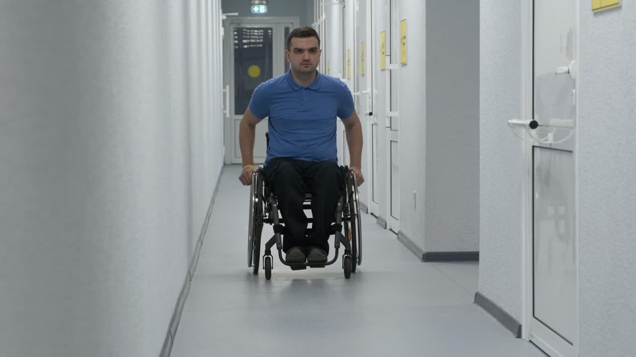 un hombre en silla de ruedas conduce por el pasillo. una persona con discapacidad se mueve por el hospital.