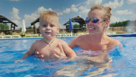 mom and the baby boy swim in the pool have fun together