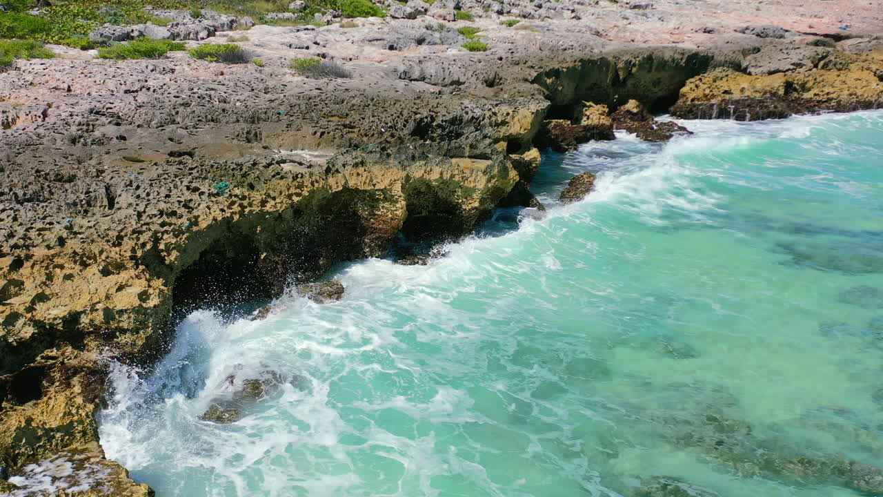 Vista aerea di onde tropicali che si infrangono violentemente su rocce appuntite in una giornata di sole a Cozumel, Messico