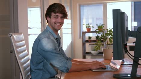 Casual-business-man-using-laptop-computer-and-looking-at-camera