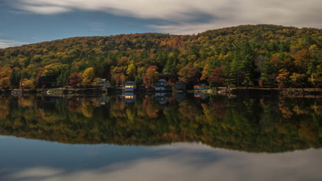 Timelapse-of-stars-rotating-across-the-night-sky-above-autumn-trees-on-a-mountain-range-above-a-calm-and-still-lake-reflecting-the-night-sky-until-mornings-dawn