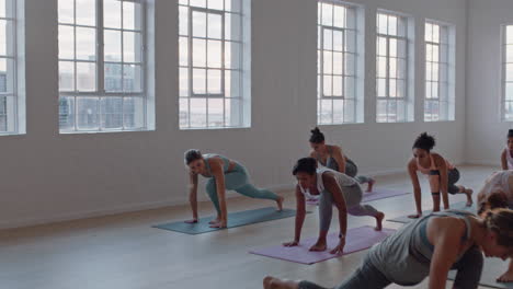 yoga-class-of-healthy-women-practicing-warrior-pose-enjoying-exercising-in-fitness-studio-instructor-leading-group-meditation-teaching-workout-posture-at-sunrise