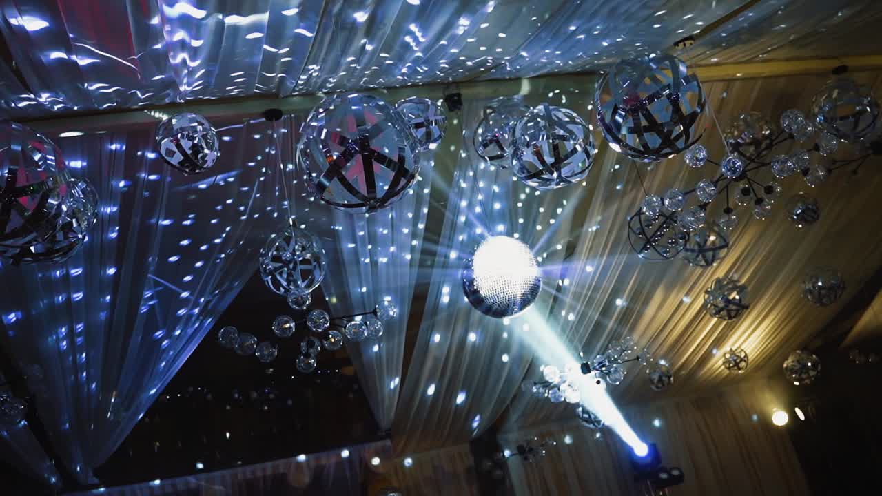 Silver light from shining balls. Disco ball glittering from the ceiling at night club. Celebration concept.