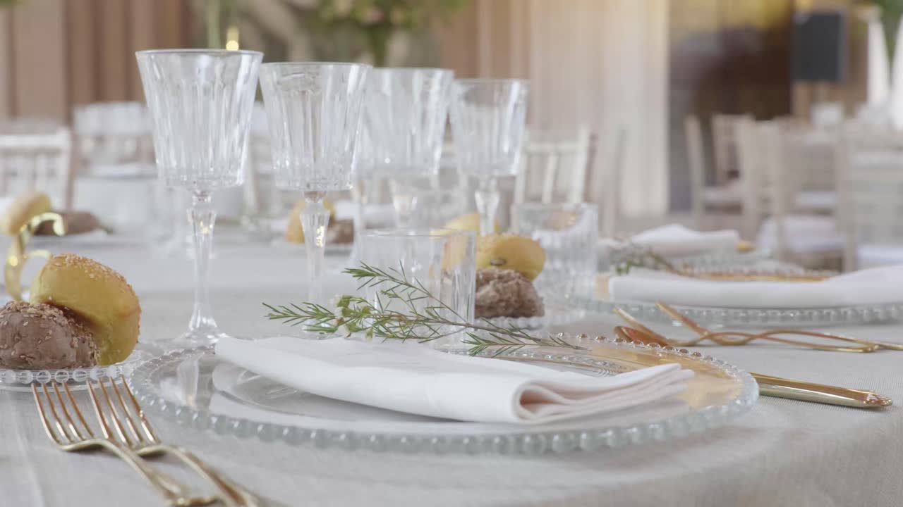 slolw 4k órbita de cerca alrededor de la mesa de la cena de la boda bellamente decorada con cubiertos de clase, vasos, pan y arreglo de flores