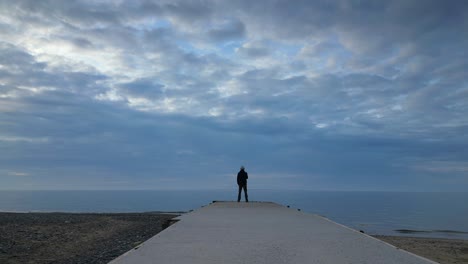 largo acercamiento al hombre estaba al final de un muelle en el anochecer en la playa de fleetwood lancashire reino unido