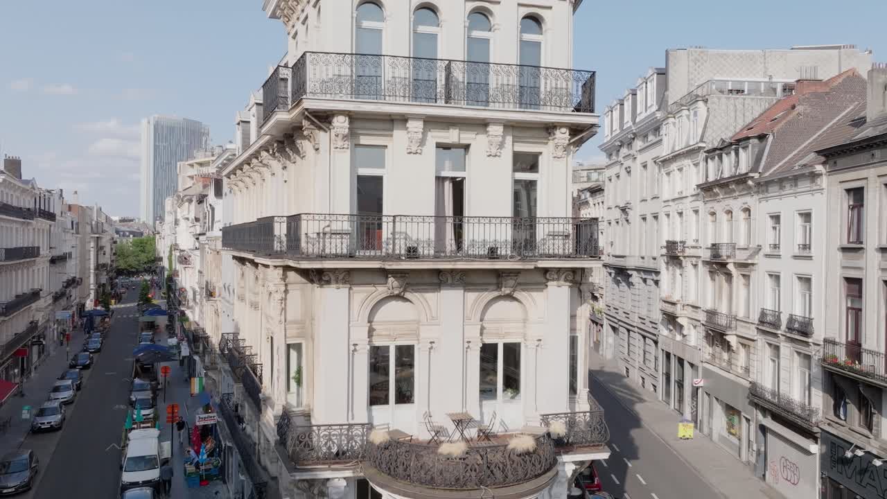 A view of a classic European-style building on a city corner with streets and cars