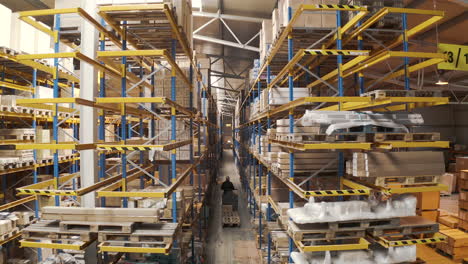 man driving an electric storage cart through a warehouse aisle,aerial