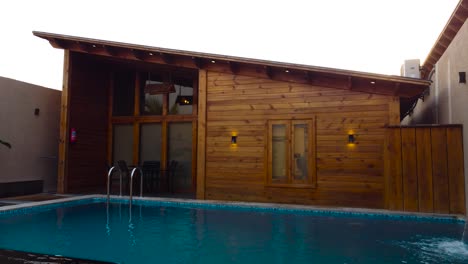 exterior of a luxurious wooden house with large windows. pool in backyard