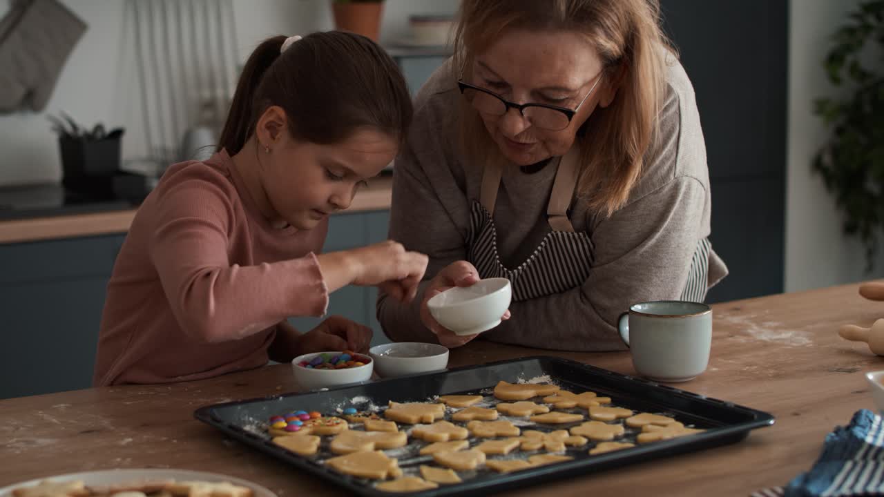 chica caucásica decorando galletas caseras con su abuela