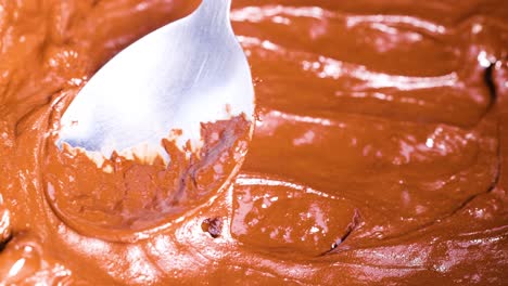 spoon stirring smooth chocolate batter in bowl