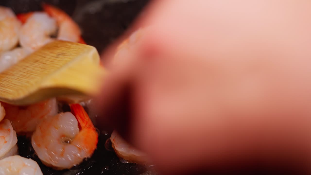Shrimp cooking in hot pan as they turn pink and release steam during sautéing process, slow motion