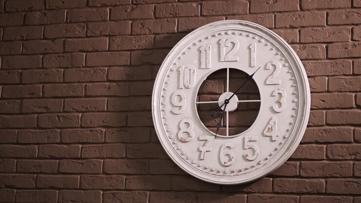 The Time Is 8.00 AM or PM on A white wall clock with a black second hand on a brown brick wall