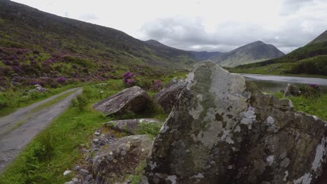 closeup footage on large boulders with opening on rural road in mountain valley during june