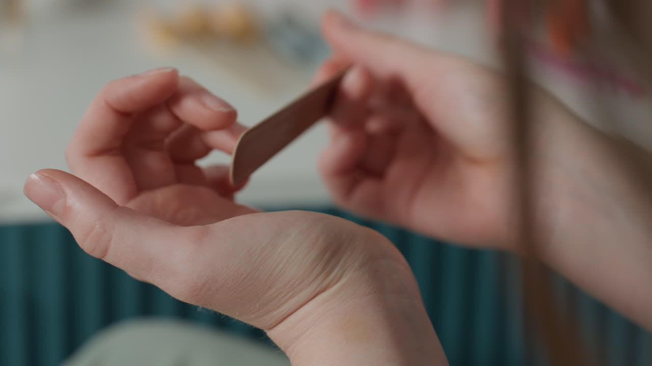 Intimate nail grooming. Soothing home wellness activity involving soft lighting and gentle buffing. Peaceful moment of selfcare featuring delicate nail smoothing under warm ambient light