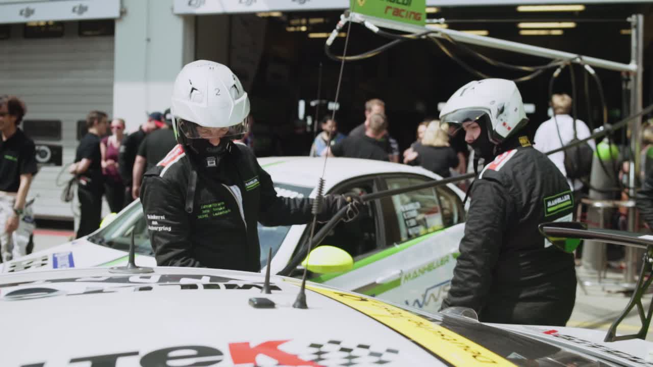 Pit crew mechanics refueling race car in pitlane paddock in sunny daylight before the start of the ADAC Nurburgring twentyfour hour race.