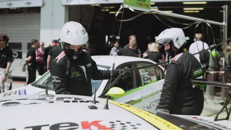 pit crew mechanics refueling race car in pitlane paddock in sunny daylight before the start of the adac nurburgring twentyfour hour race.